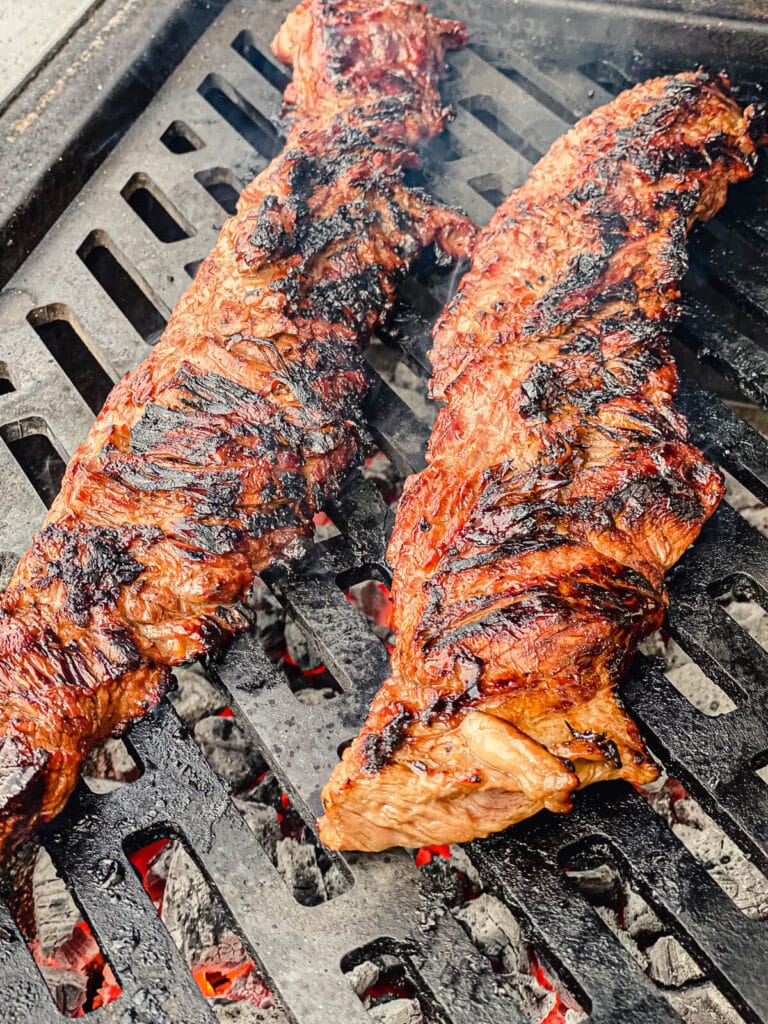charred skirt steaks on a grill grate