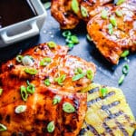 Hawaiian huli huli chicken thighs on a cutting board with grilled pineapple