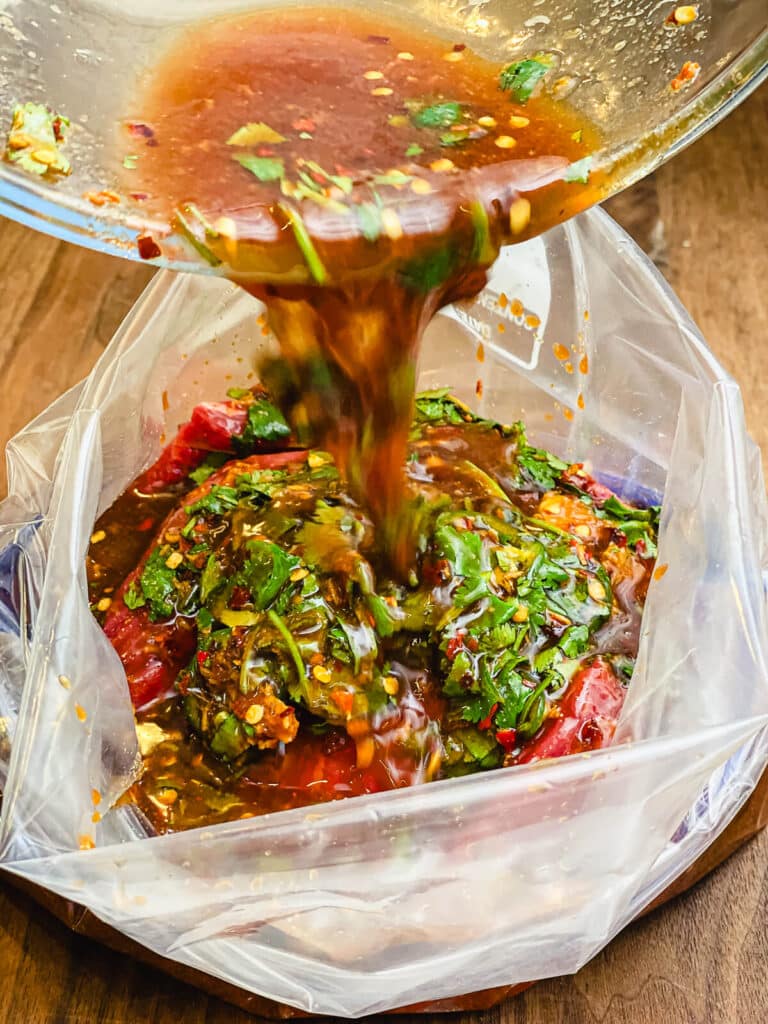 marinade being poured onto pieces of flap meat in a plastic bag