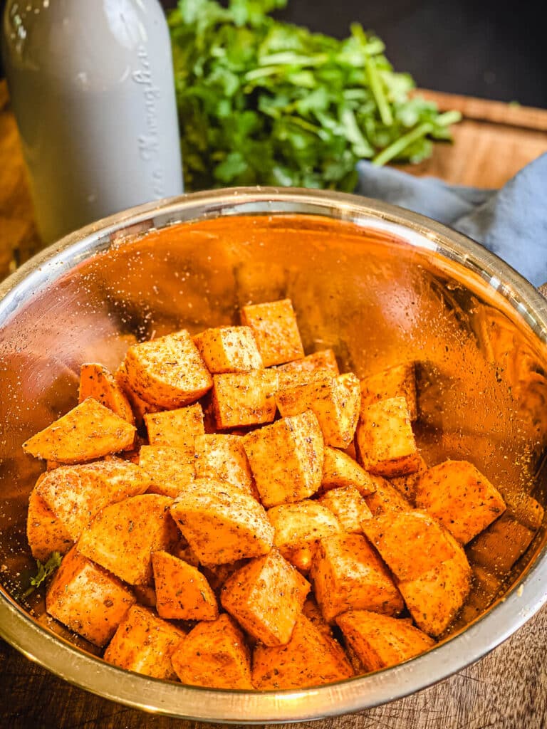 raw sweet potato cubes in a bowl with seasoning