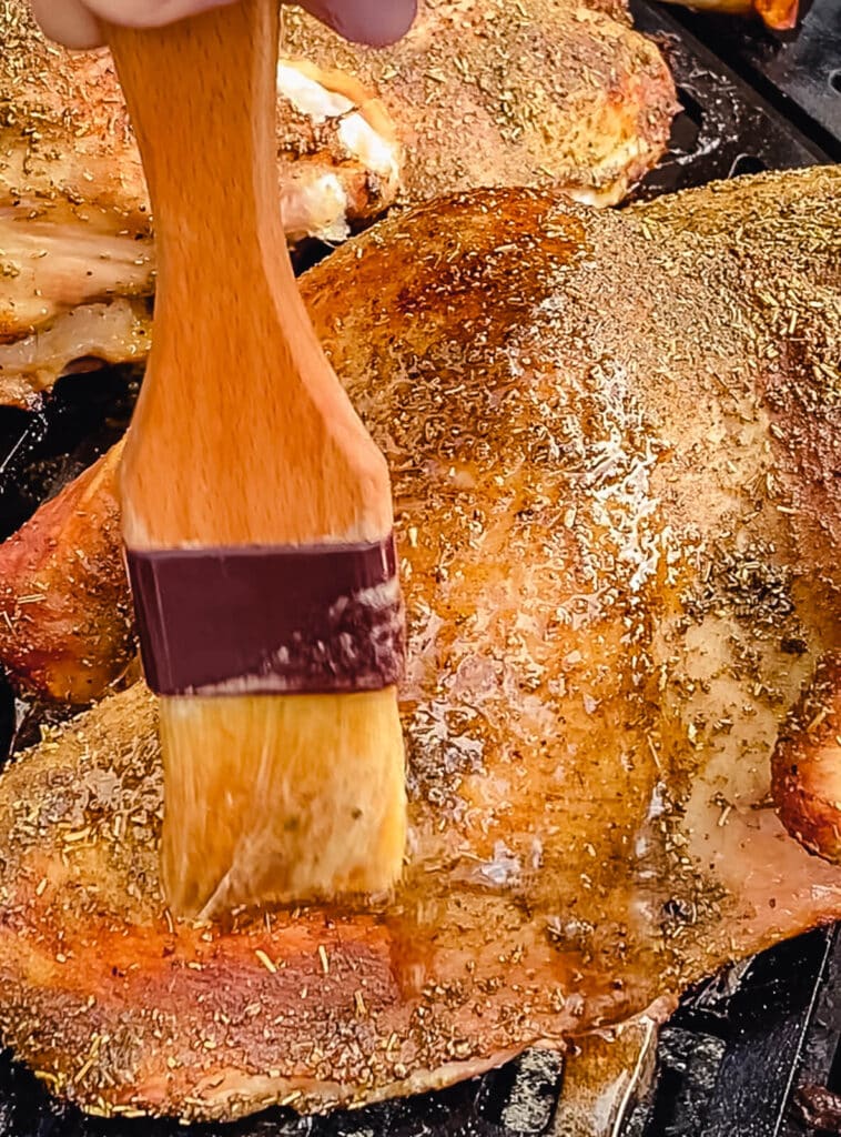 basting a roasted turkey on the grill