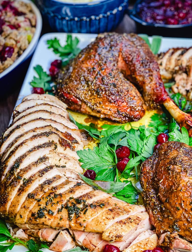 sliced turkey breast on a platter with parsley and cranberries 