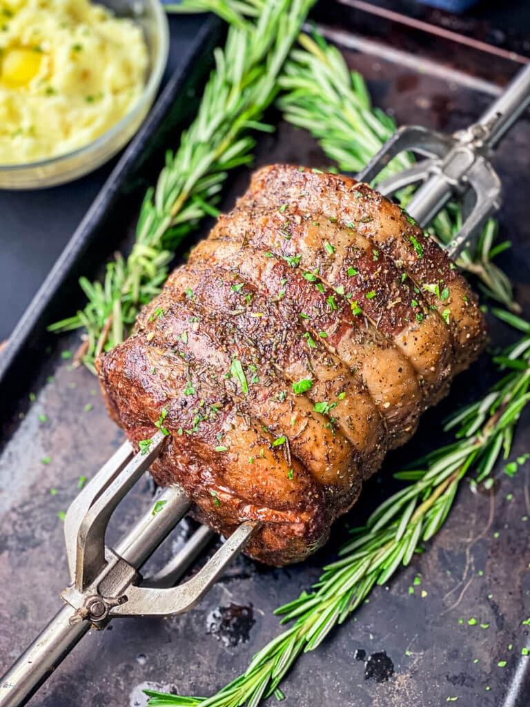 rotisserie prime rib on a spit, sitting on a baking sheet