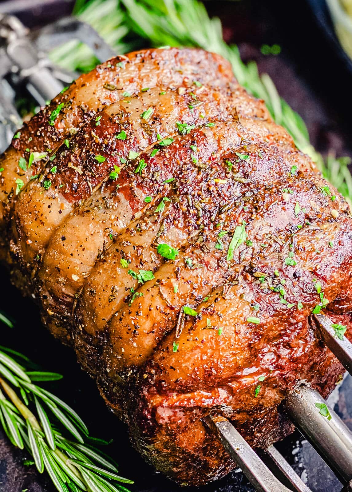 cooked rotisserie prime rib on a spit with rosemary