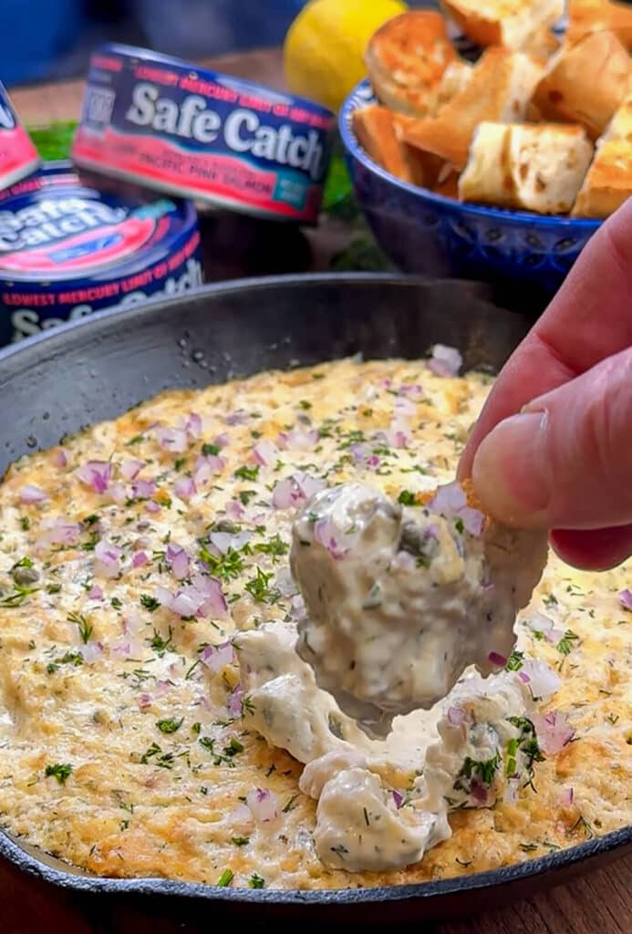 toasted bagel scooping up smoked salmon dip