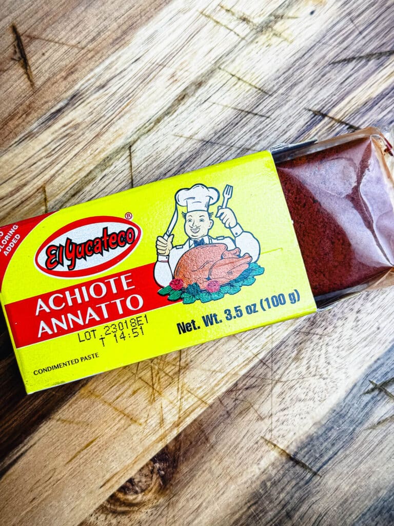 achiote paste in a box sitting on a wooden cutting board