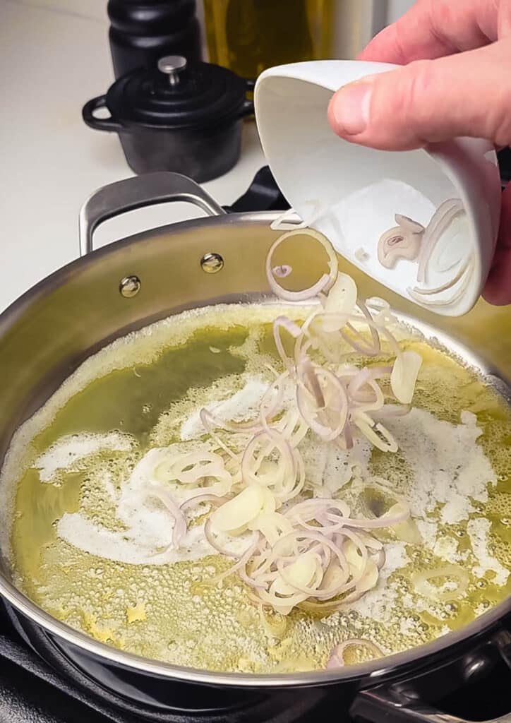 shallots being added to a pan of melted butter