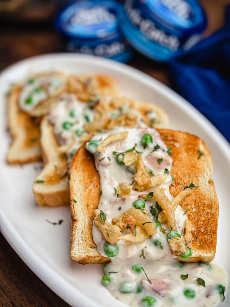 creamed tuna on toast with peas on a white plate