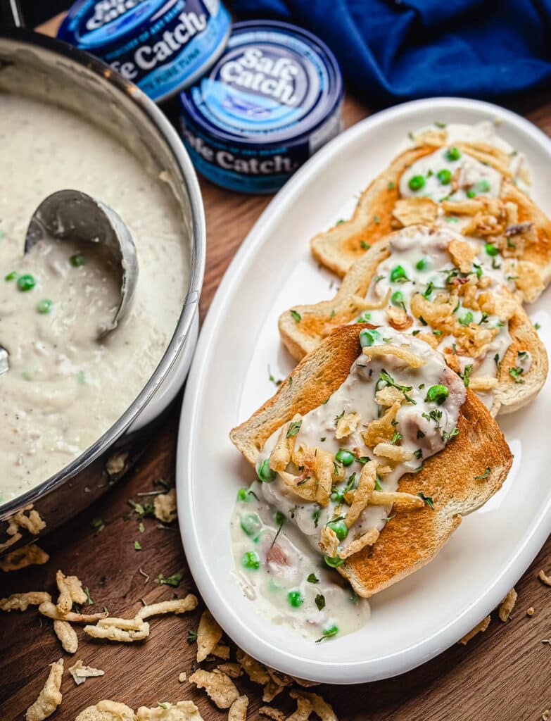 creamed tuna on toast with cans of tuna in the background