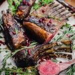 grilled rack of lamb chops on a platter with herbs and pomegranate