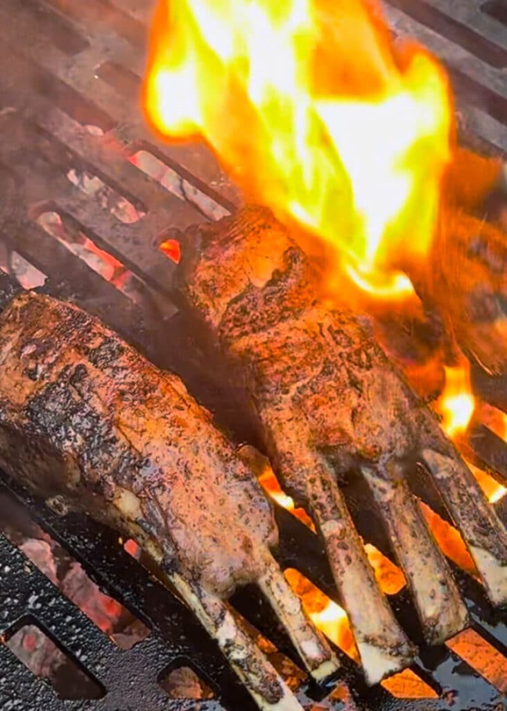 lamb rib chops on a grill with fire flaring up