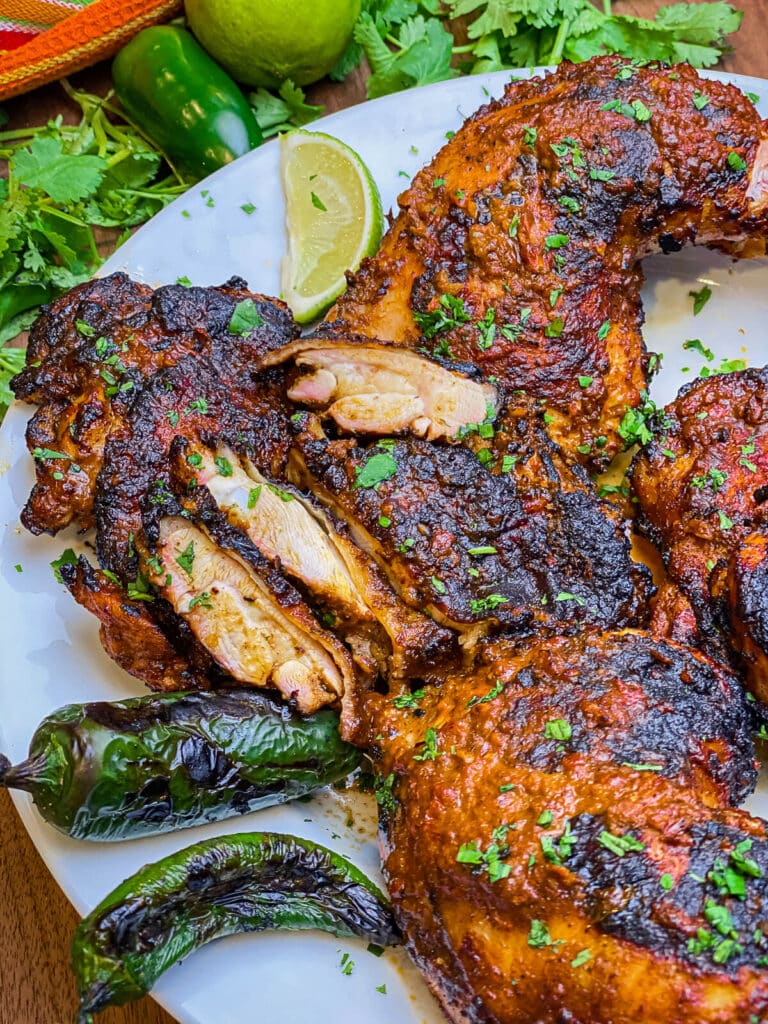 sliced chicken thighs on a plate with charred jalapeños 