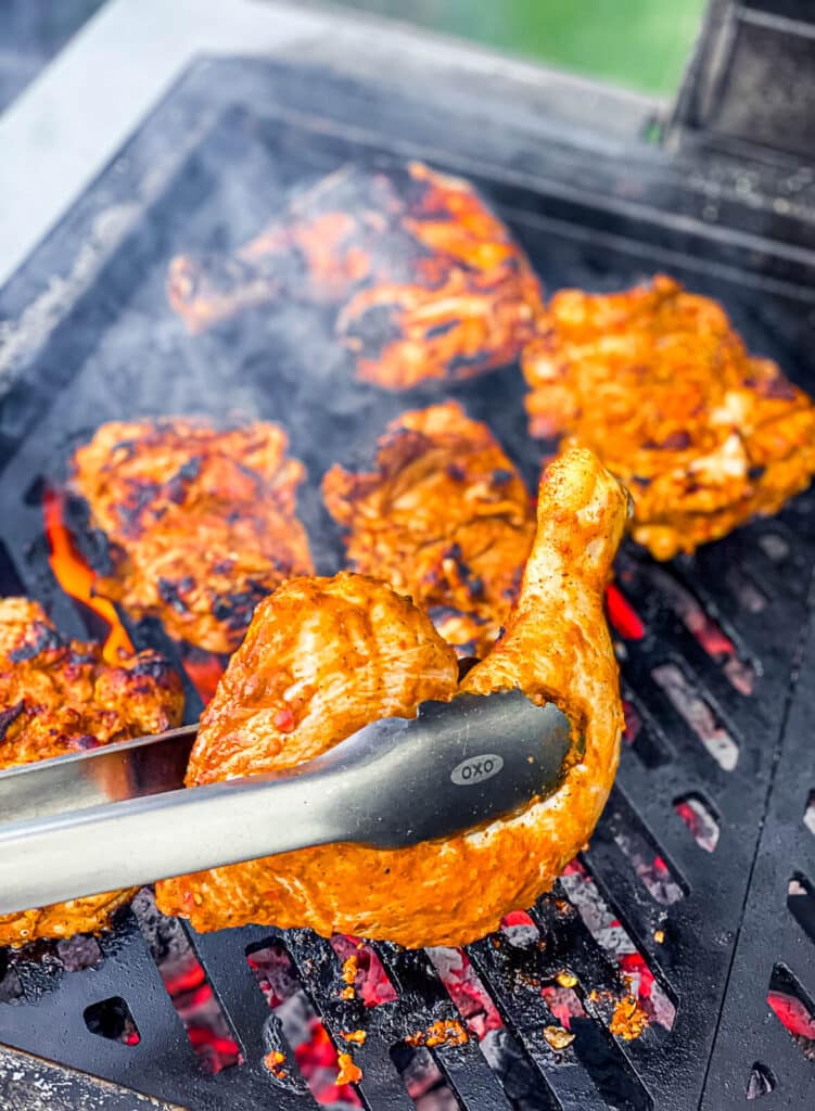 chicken being flipped on a grill with tongs