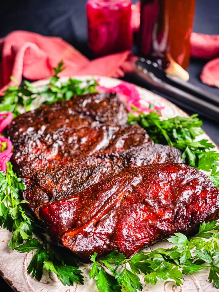 pork steaks on a platter with bbq sauce and fresh herbs