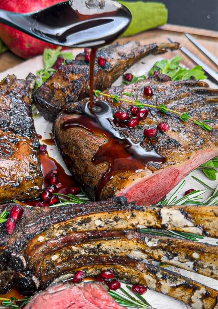 pomegranate glaze being drizzled onto rack of lamb 