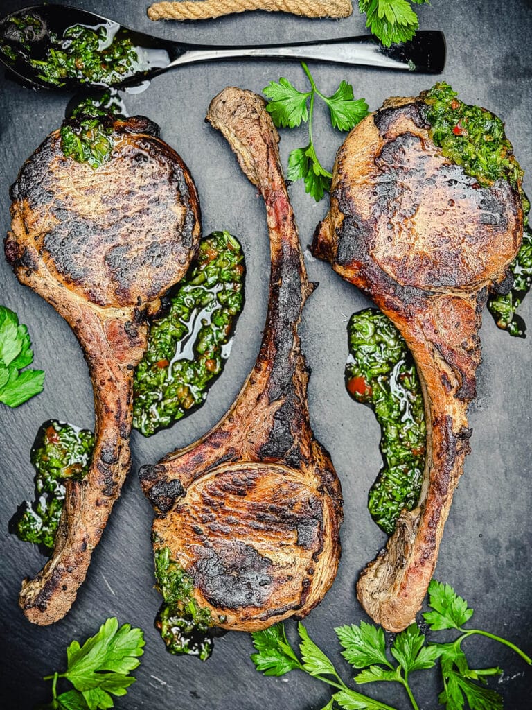 platter with grilled tomahawk pork chops and chimichurri sauce