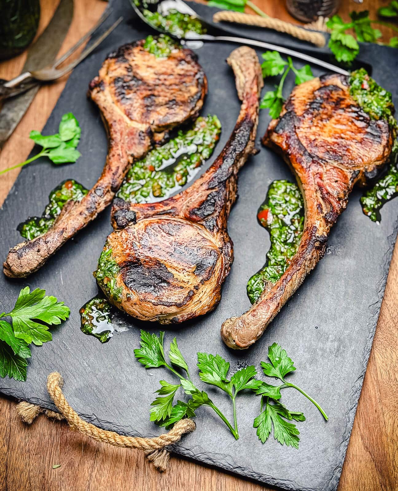 black slate cutting board with tomahawk pork chops and herbs