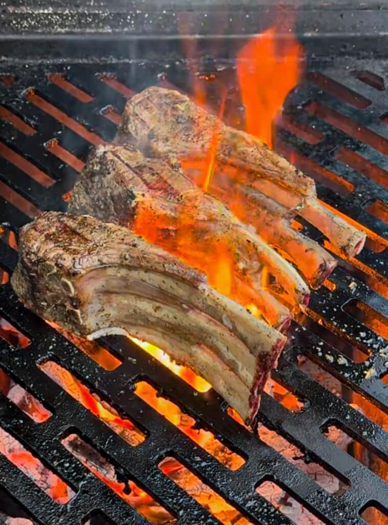 lamb rib chops searing on a grill over flames