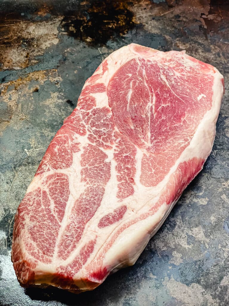 uncooked pork steak on a baking sheet