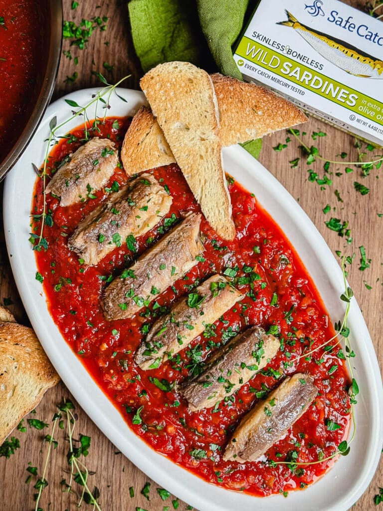 overhead shot of sardines fra diavolo on a platter with herbs