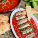 Sardines fra diavolo on a platter with bread and herbs