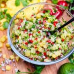 glass bowl of pineapple salsa with black spoon and cilantro
