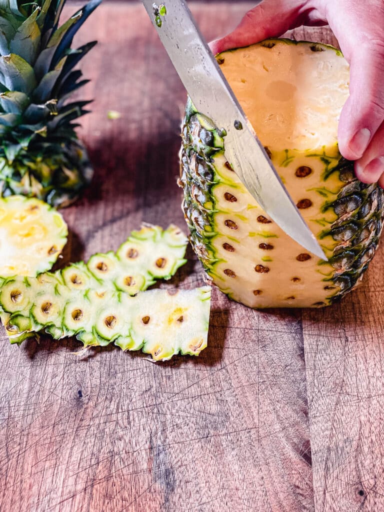 knife cutting into a pineapple for a pineapple salsa recipe