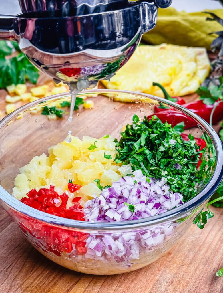 lime juice being squeezed into fruit salsa