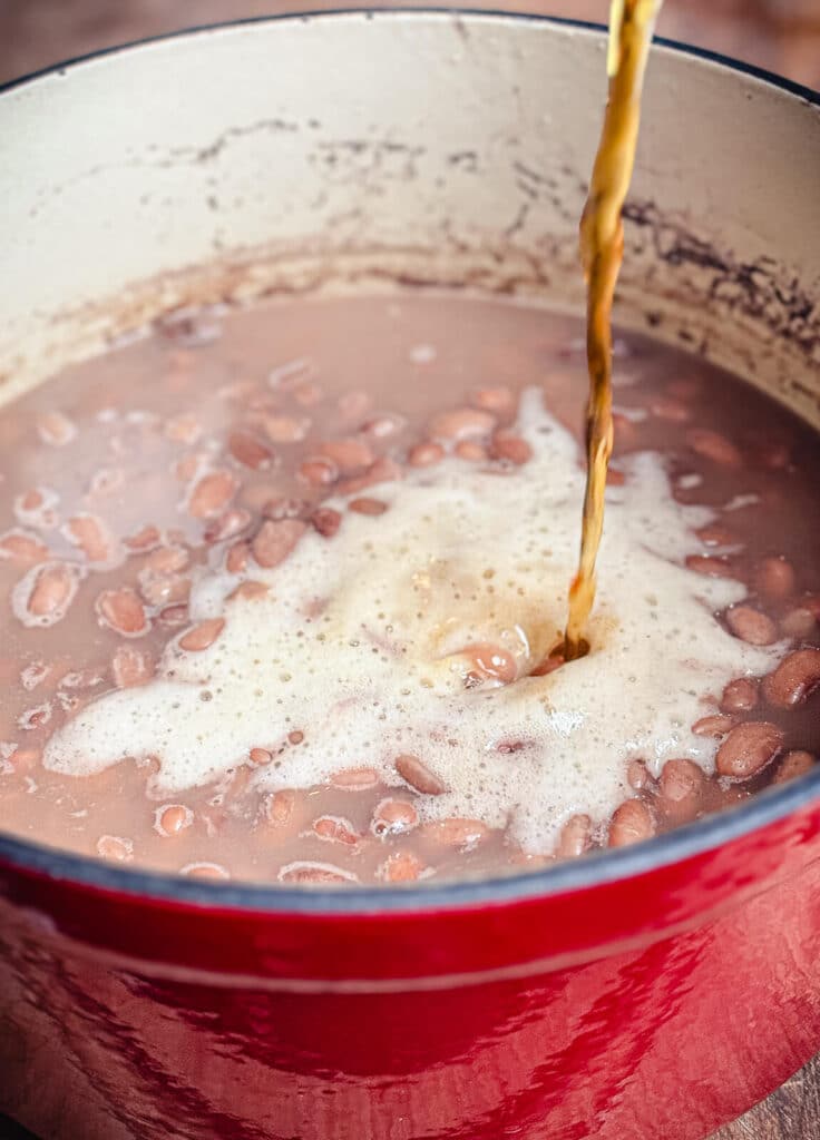 beer being poured into a pot of beans