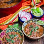 two bowls of borracho beans with condiments