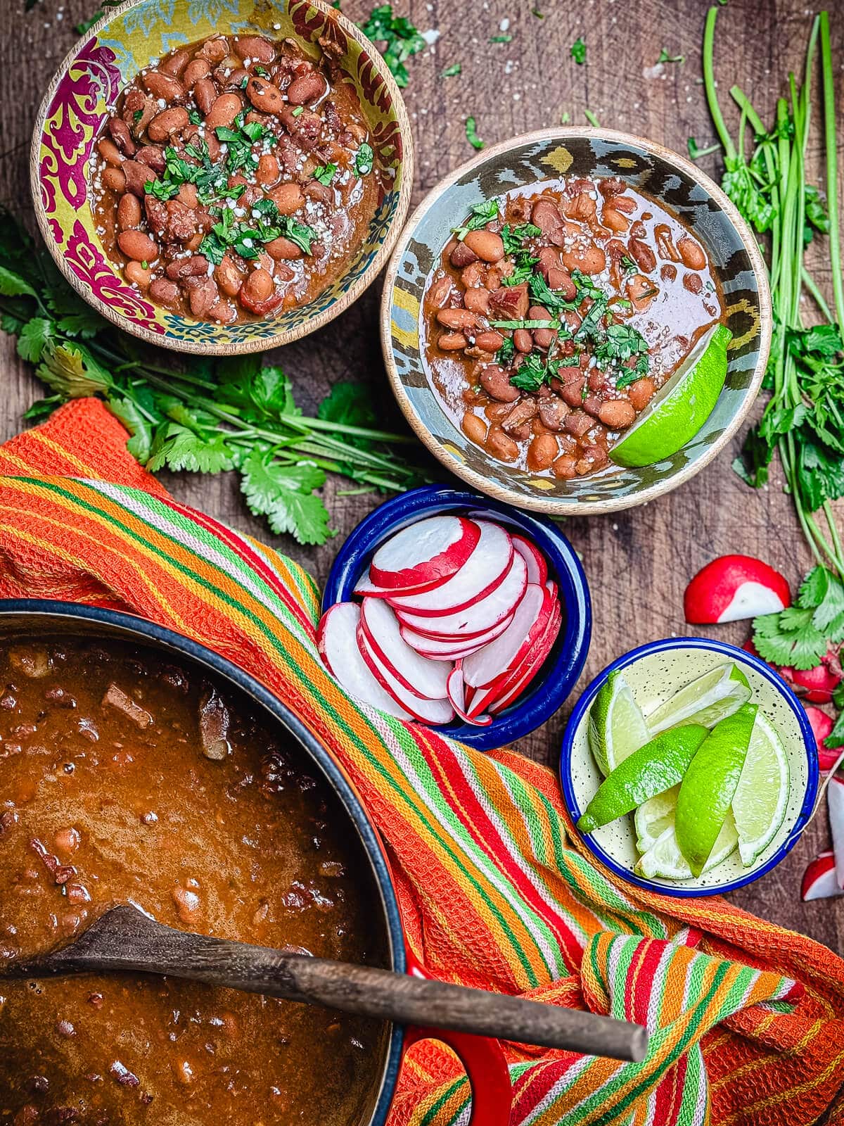 borracho beans in two bowls with radishes and limes