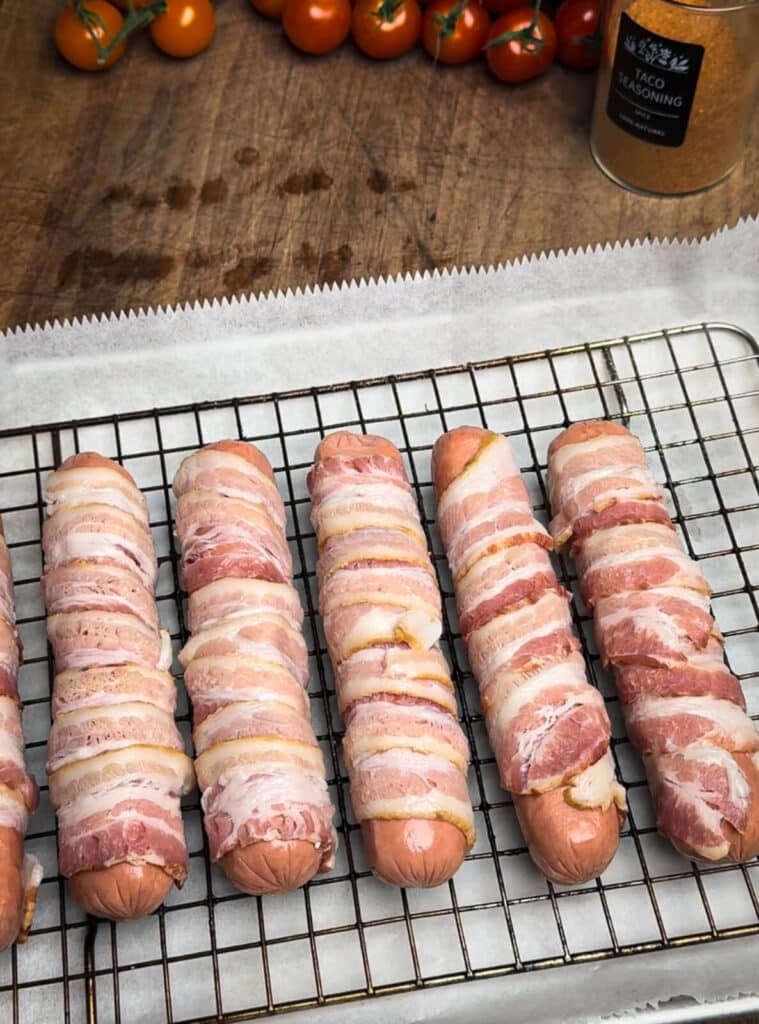 hot dogs wrapped in bacon on a cooling rack