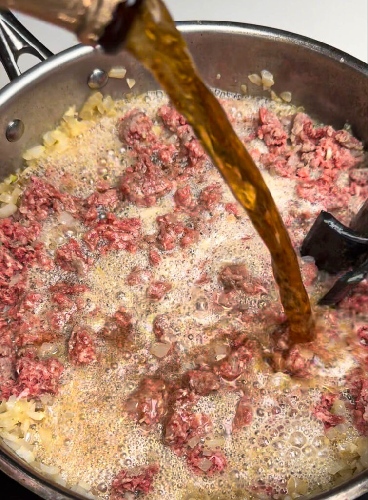 beer being poured into chili for taco dogs