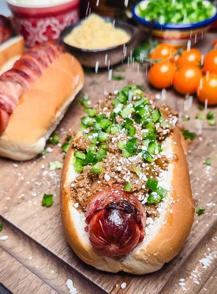 cheese being sprinkled on a taco dog