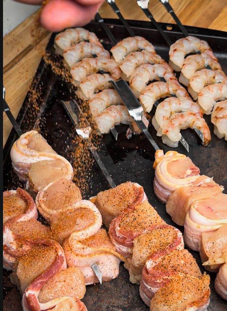 chicken and bacon skewers being seasoned