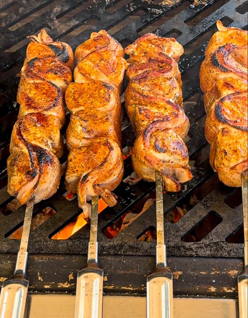 charred chicken and bacon skewers on a grill