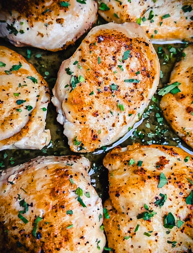 seared chicken breasts in a pan sauce with parsley