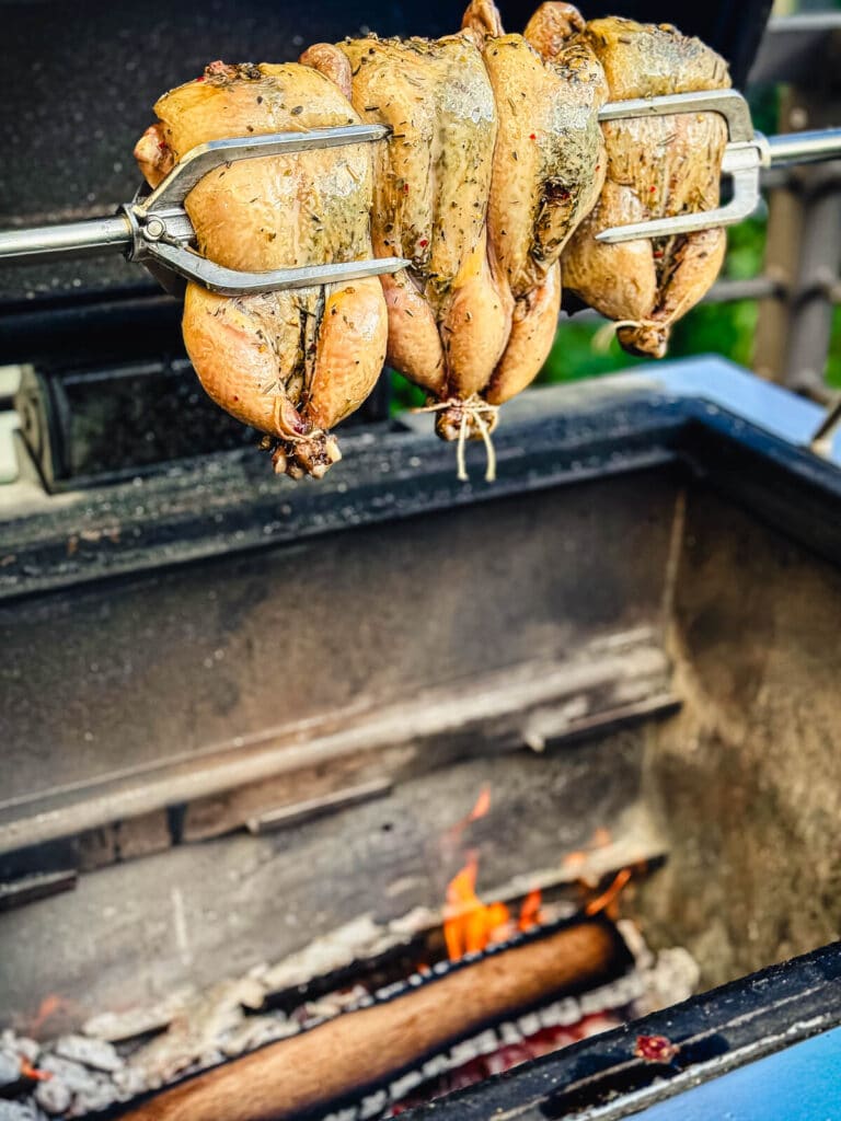 Cornish hens spinning on a rotisserie over a wood fire
