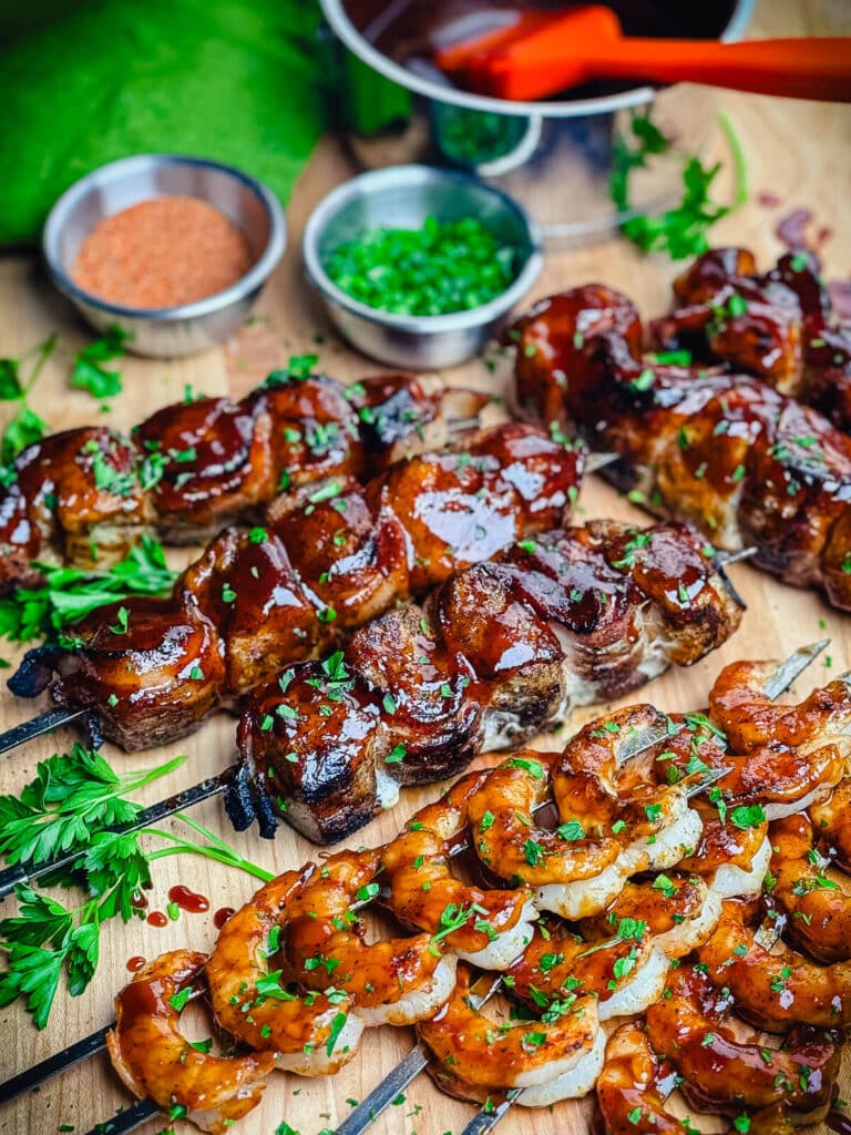 chicken and bacon skewers with grilled shrimp on a cutting board