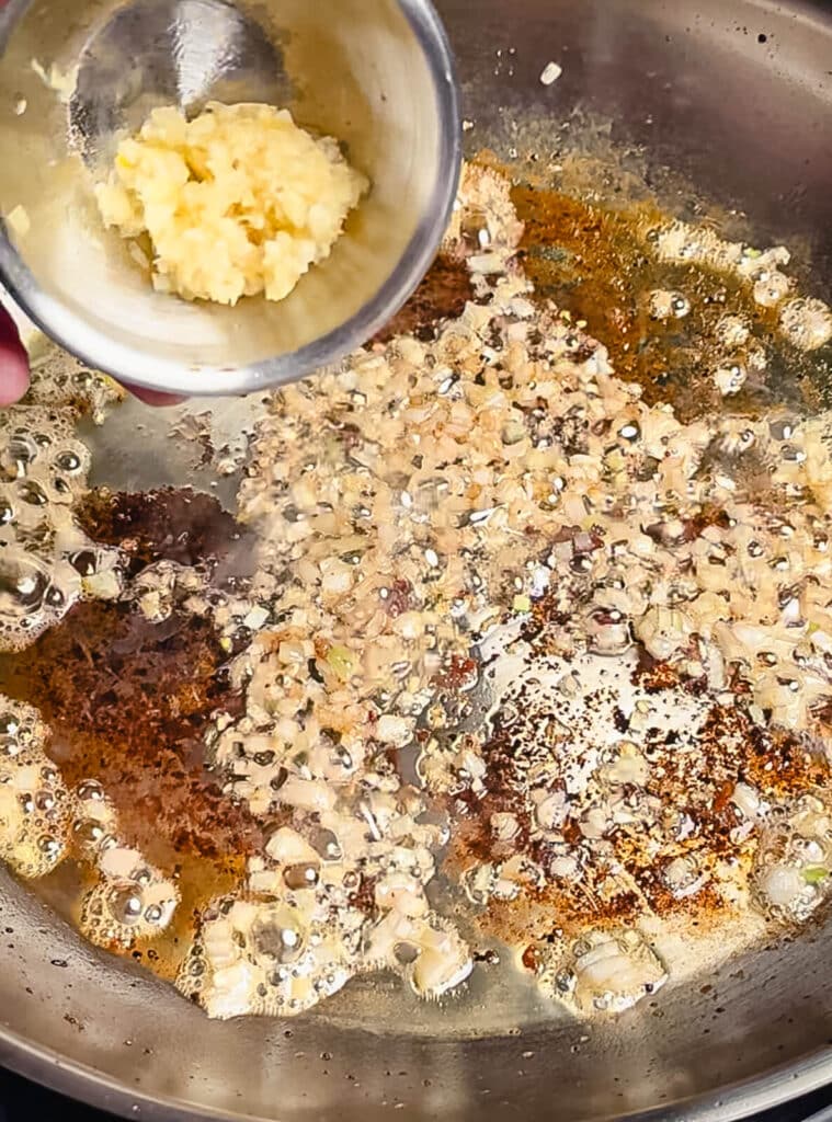 garlic being added to a chicken pan sauce