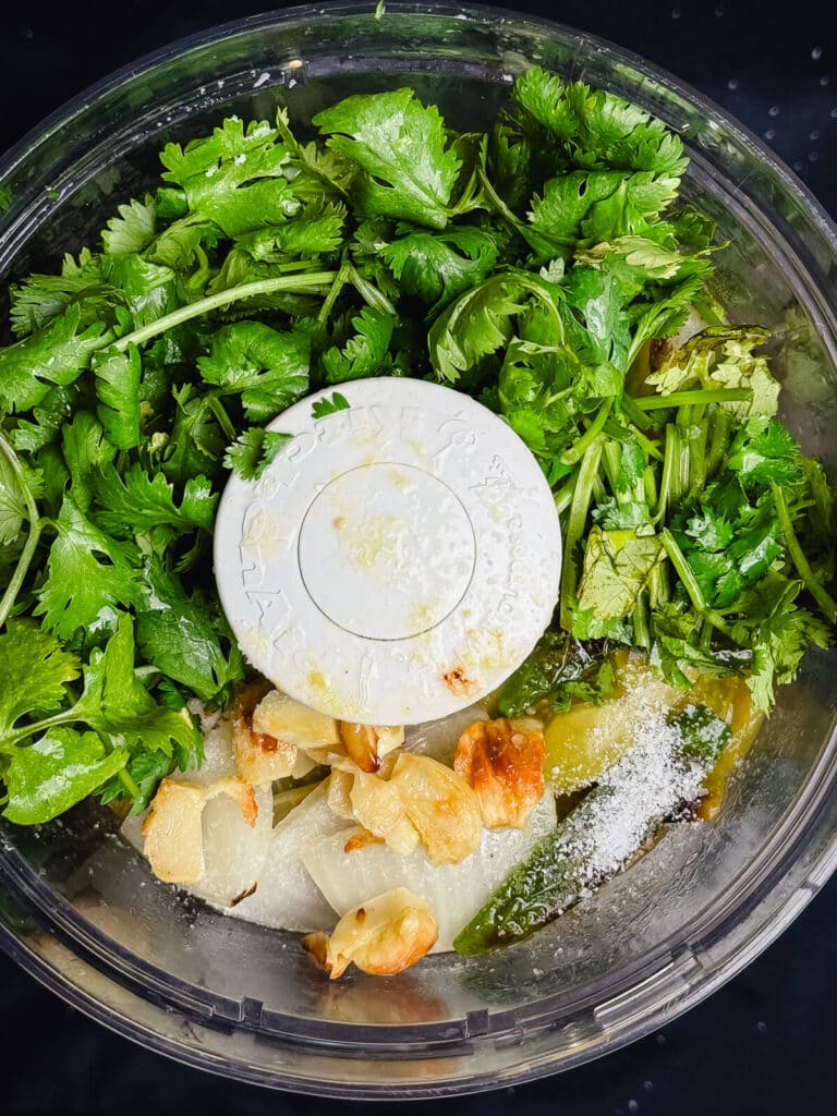 food processor filled with ingredients for salsa verde