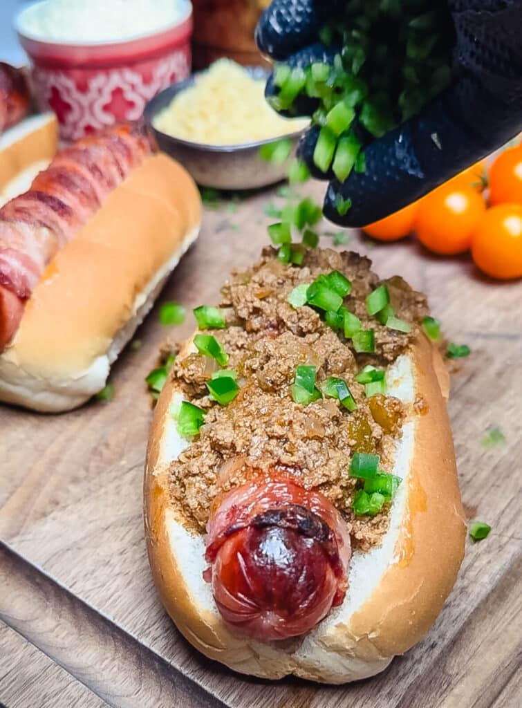 jalapeños being added to a taco dog