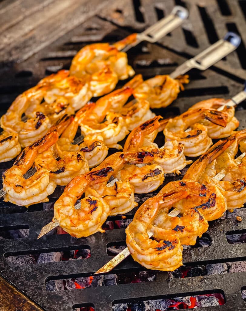 glazed skewered shrimp on the grill over red 
hot coals