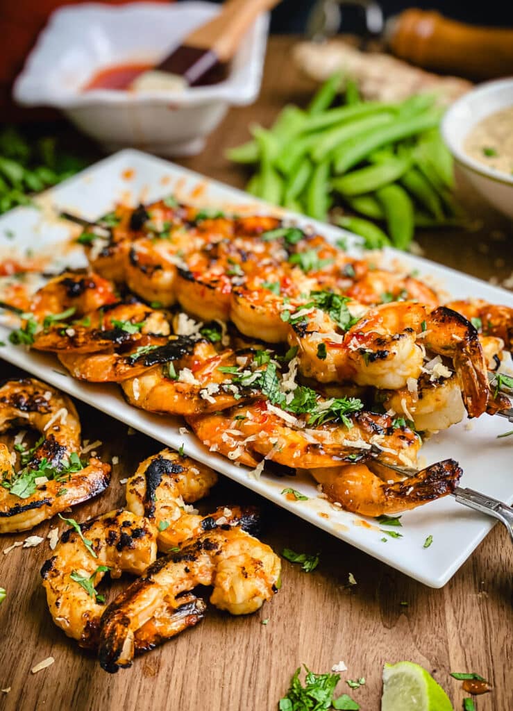 grilled shrimp on a platter with a bowl of sweet chili glaze in the background