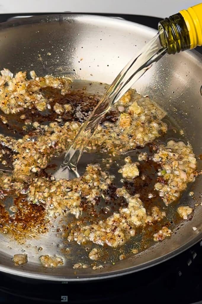 wine being poured into a pan to deglaze it