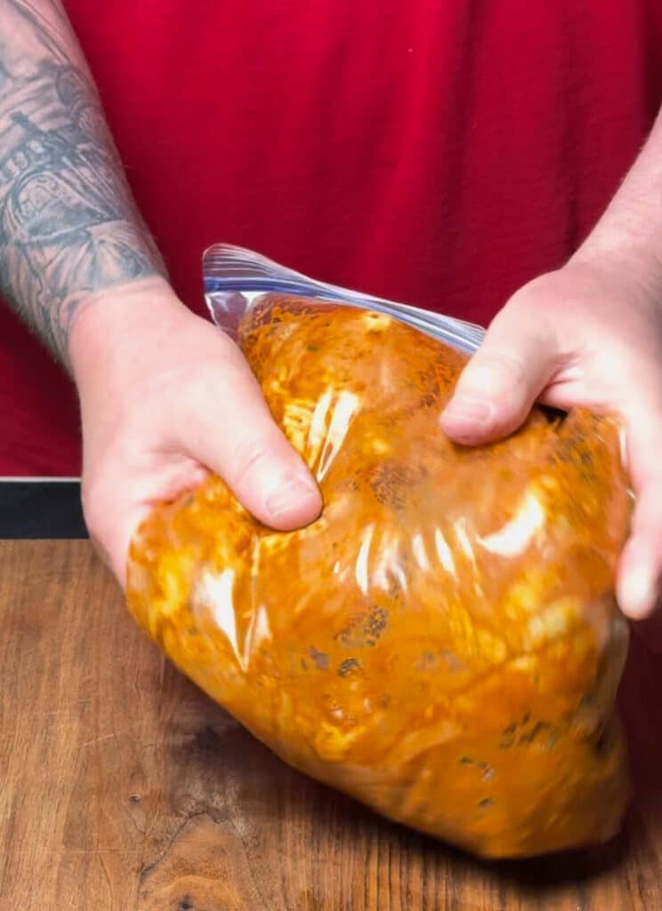 massaging marinade into chicken in a bag