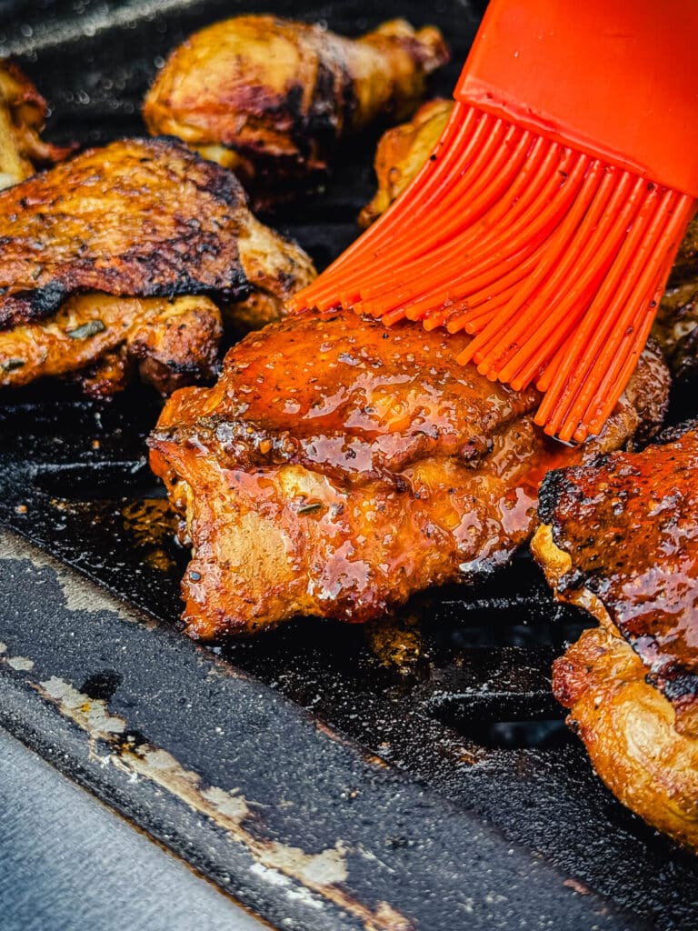 peruvian chicken being glazed over indirect heat