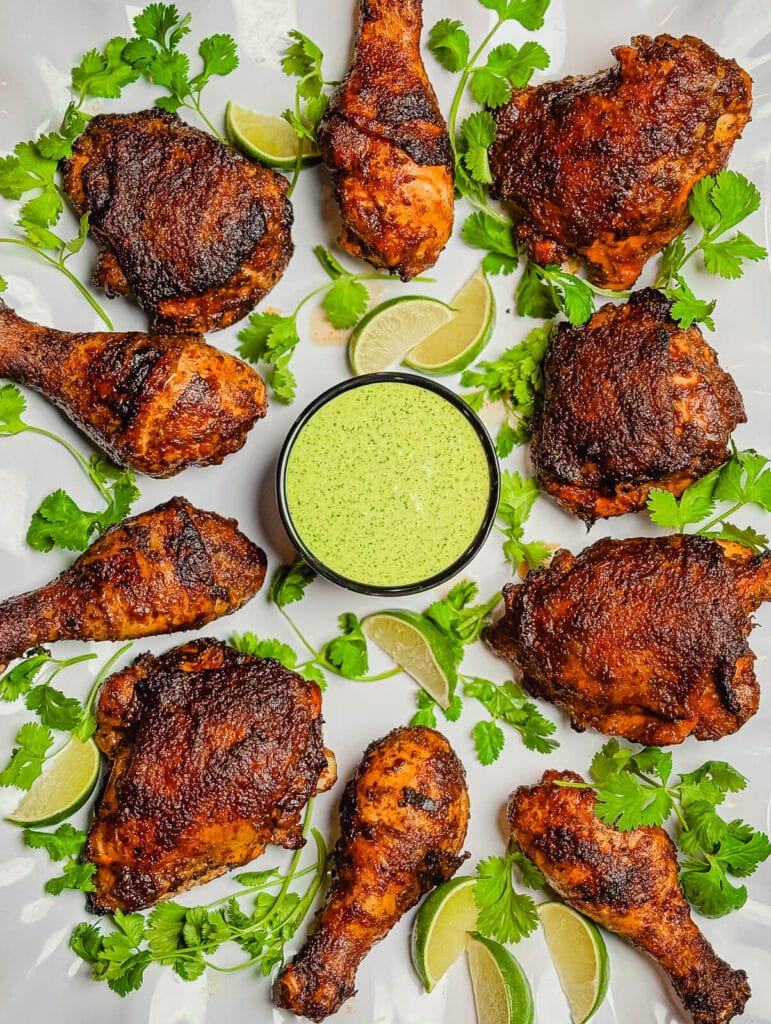 grilled peruvian chicken on a platter with cilantro and limes