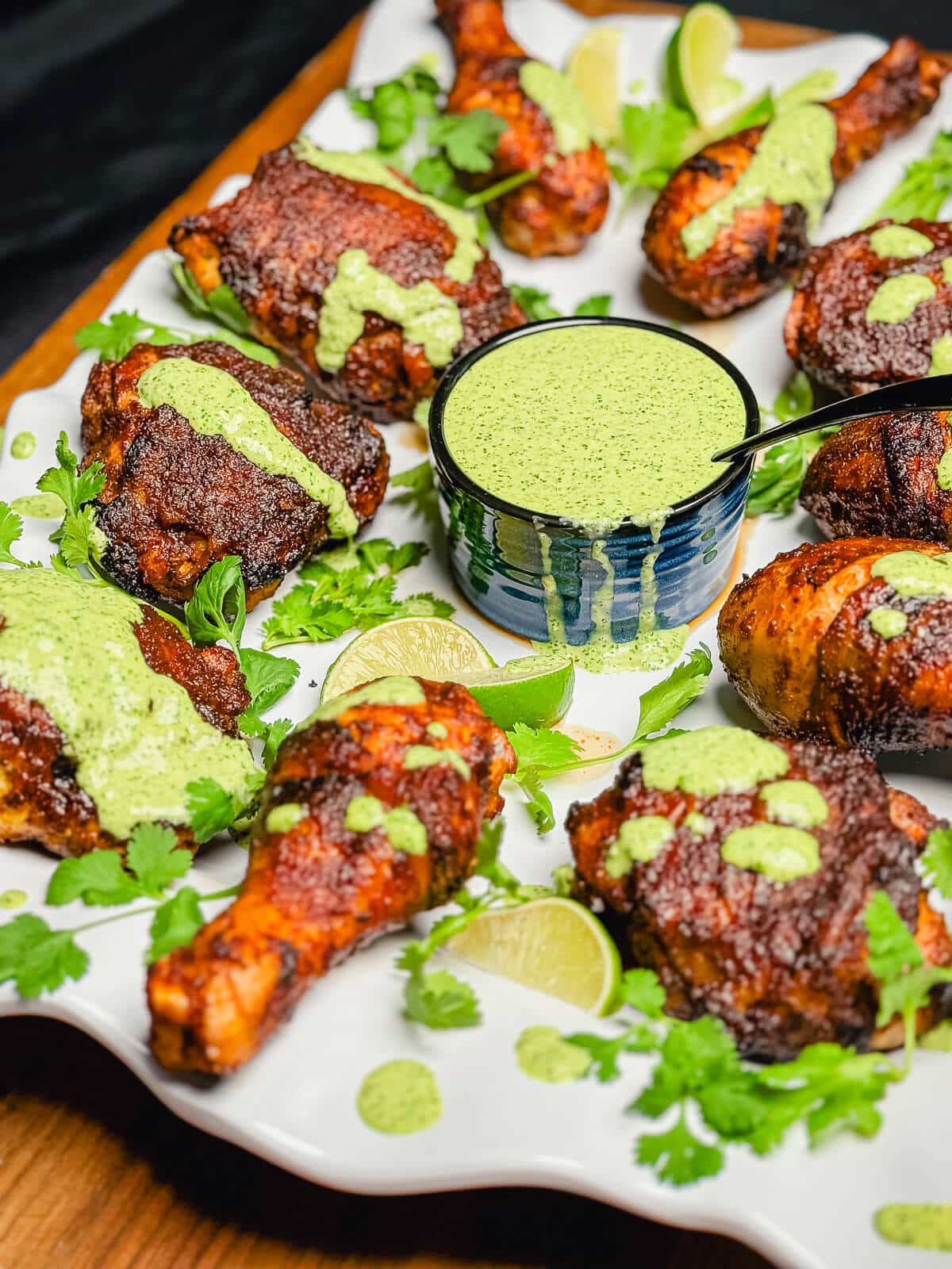 peruvian grilled chicken on a platter with green sauce on the chicken