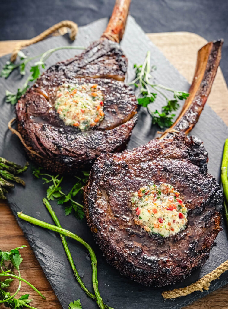 pads of bacon butter on top of charred ribeye steaks